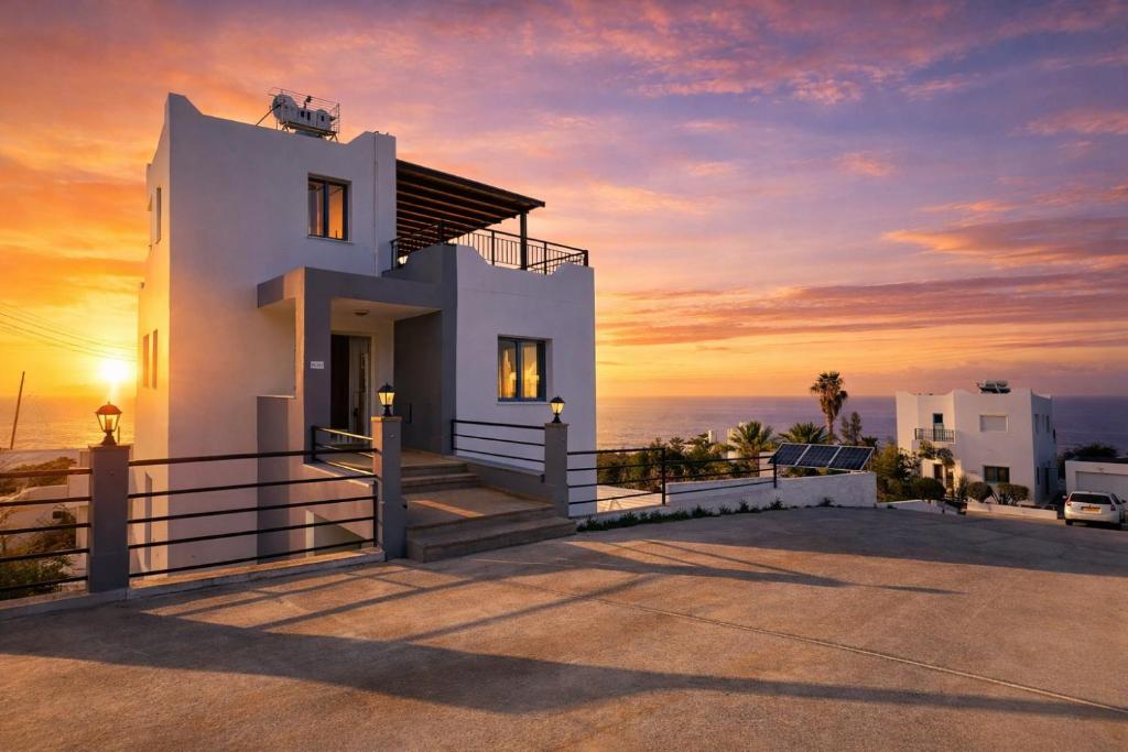 a white house with the sunset in the background at Livia - Vikles Villas in Pomos