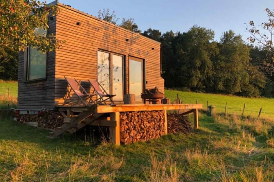 a tiny house sitting on top of a field at La Tiny De Fy in Aywaille