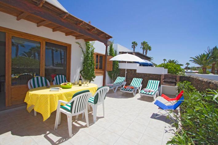 een patio met een tafel met stoelen en een parasol bij Playa Flamingo B in Playa Blanca