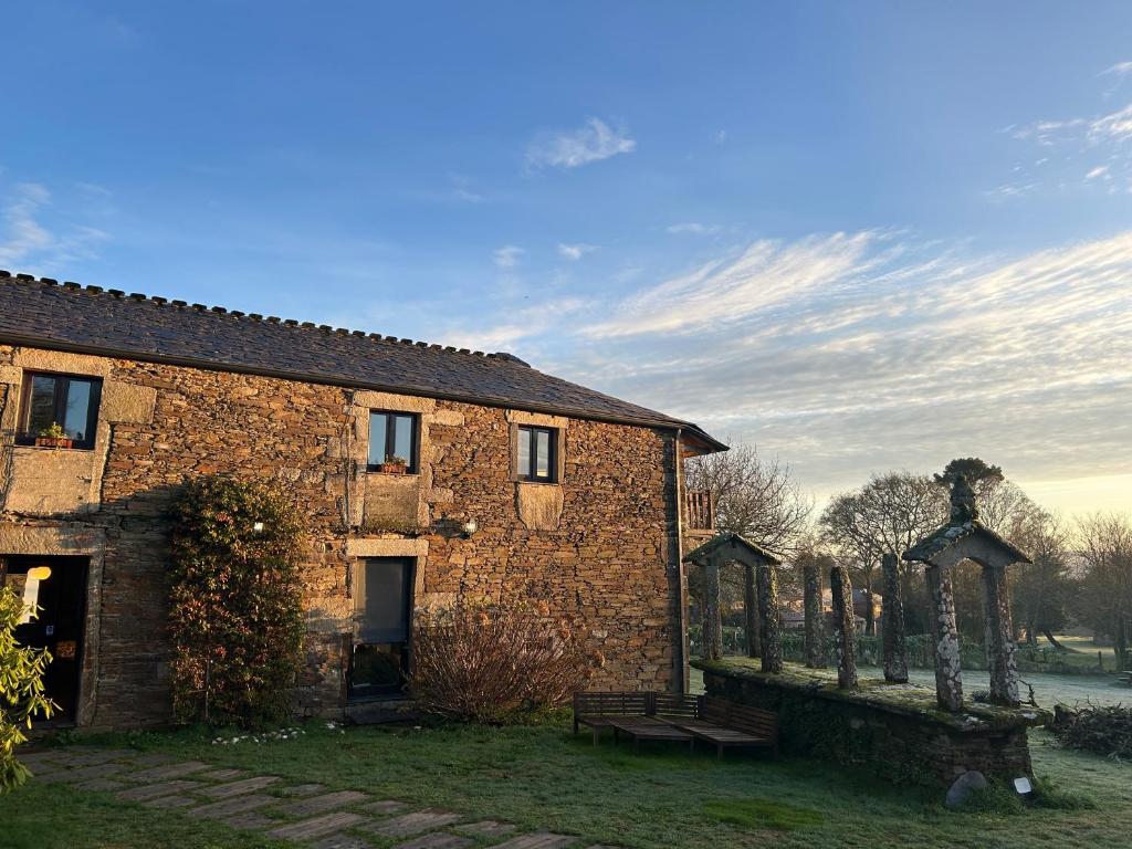 an old brick building with a bench in front of it at Casas do Campo in Monfero