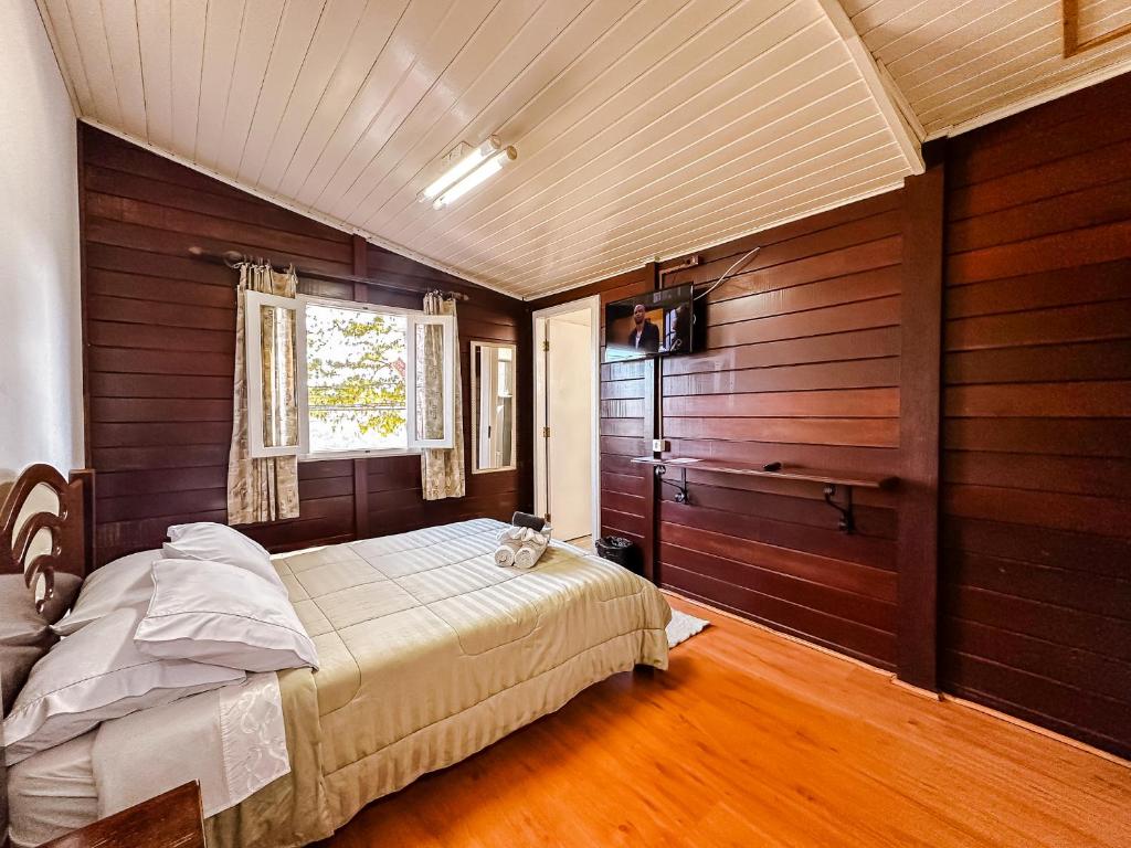 a bedroom with a bed in a room with wooden walls at Pousada do Vento in Campos do Jordão