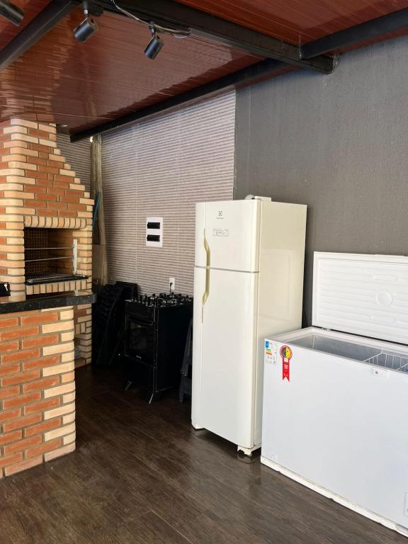 a white refrigerator in a garage next to a brick wall at Edicula para temporada in Piracicaba