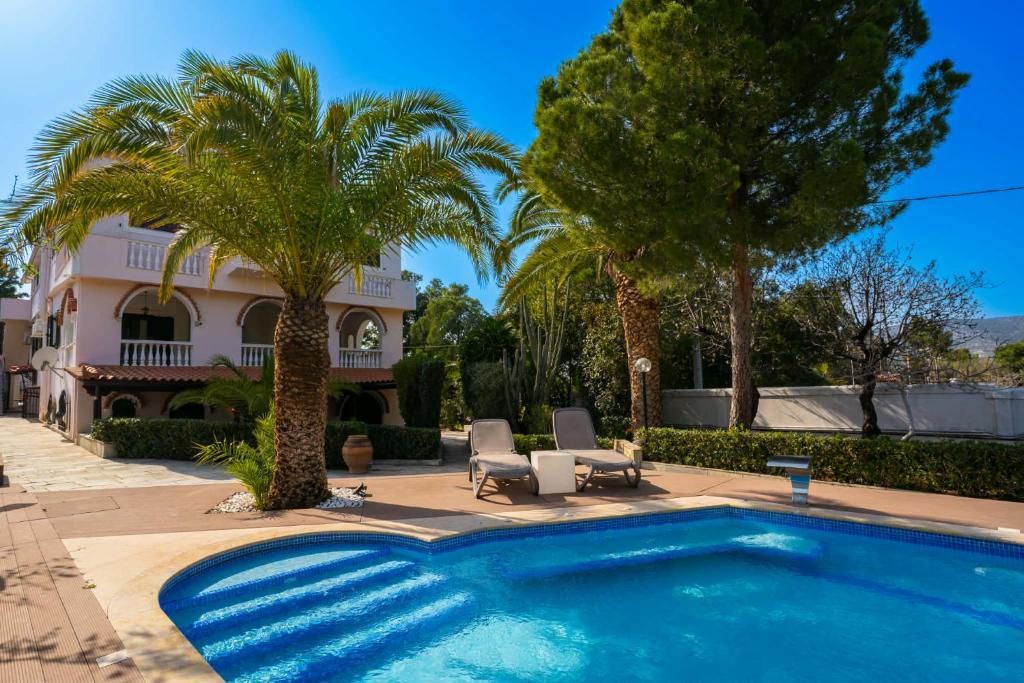 a swimming pool in front of a house with palm trees at Gkr Luxury Villa in Aghia Marina