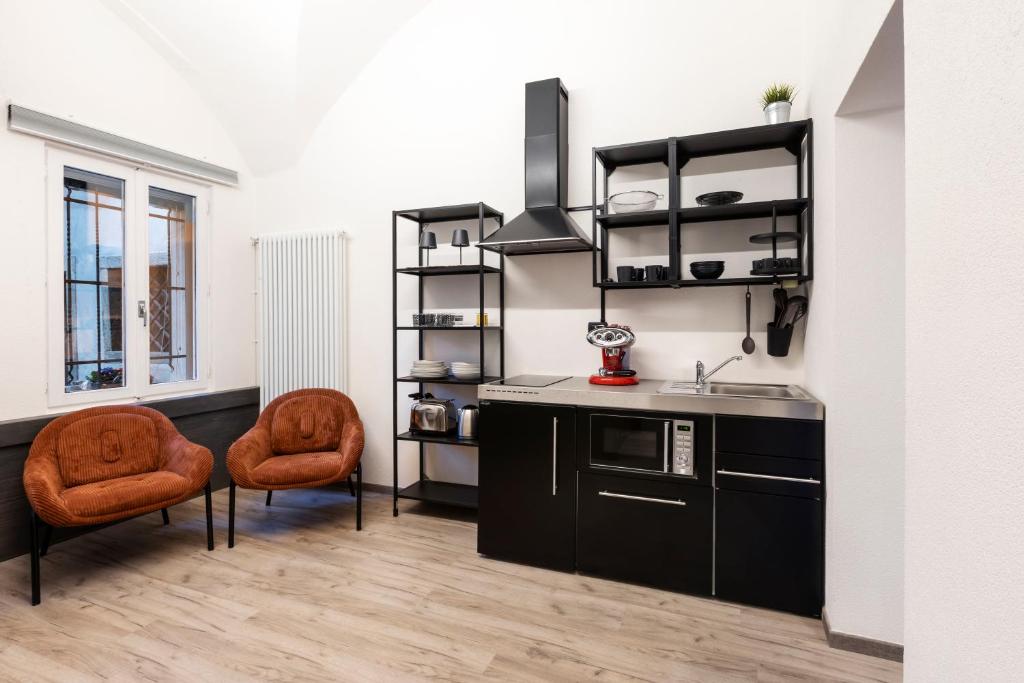 a kitchen with two orange chairs and a sink at Ca' Lumaga -Charming Holiday Studio in Chiavenna