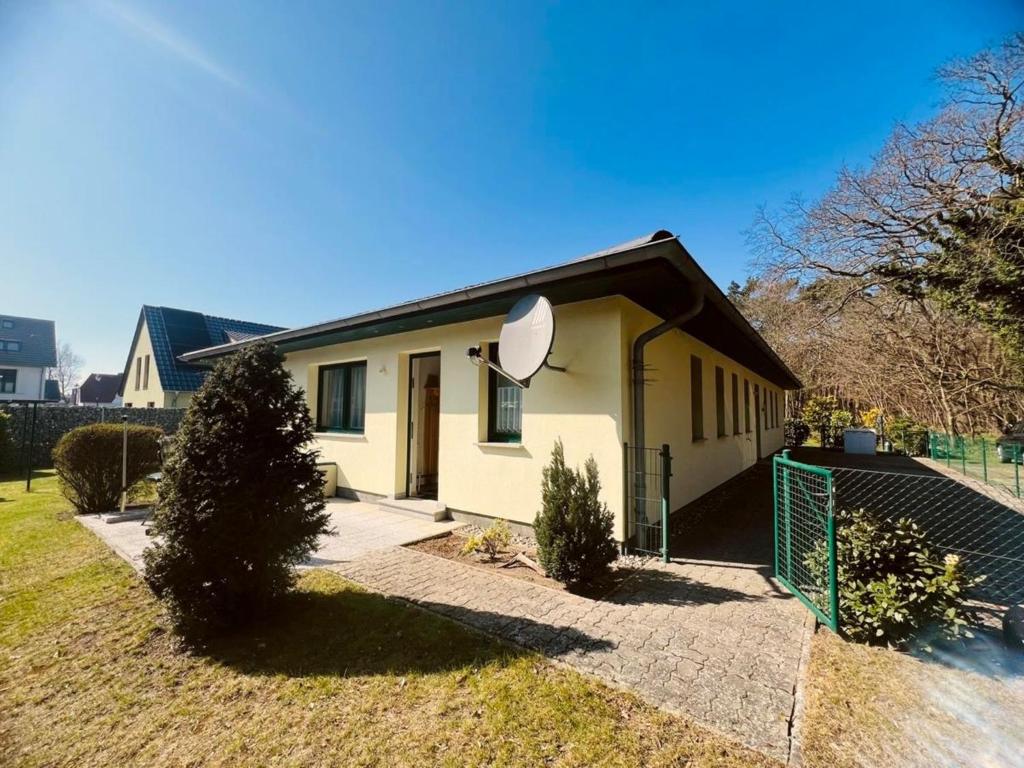 a small white house with a fence in a yard at Ferienwohnung Westi in Thiessow