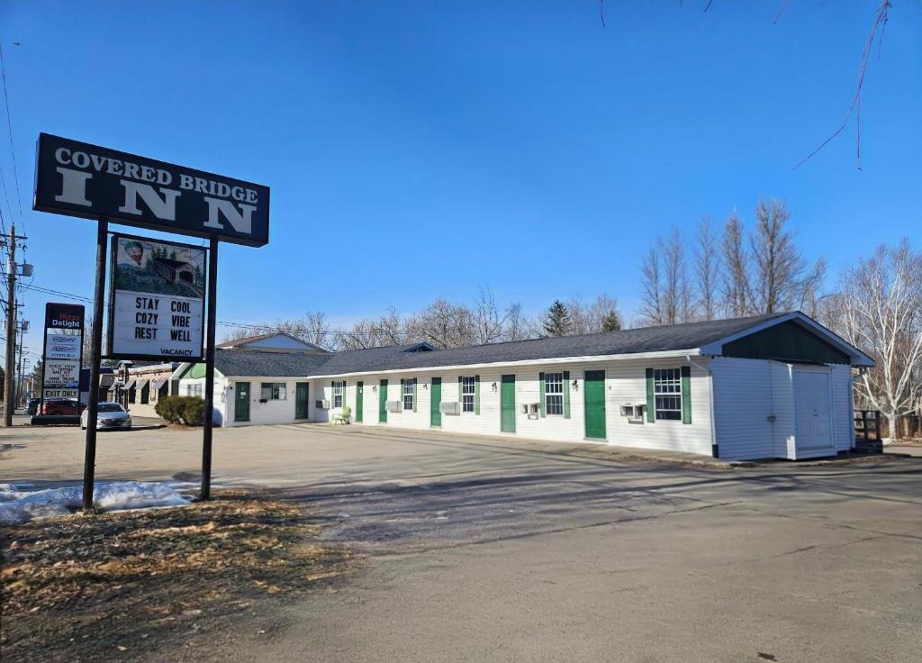 a white building with a sign in front of it at Covered Bridge Inn in Sussex