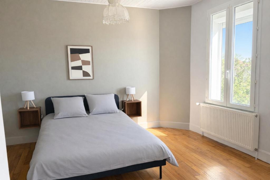 a bedroom with a bed with two lamps and a window at La Parenthèse in Sagy