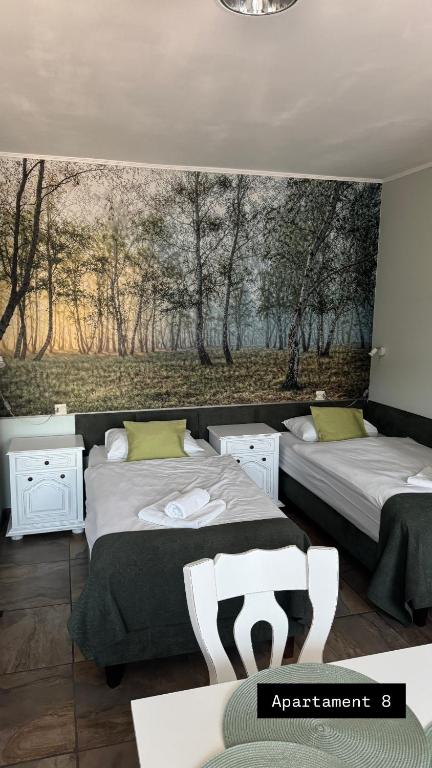 a bedroom with two beds and a painting on the wall at Apartamenty Jaskinia Solna in Ruda Śląska
