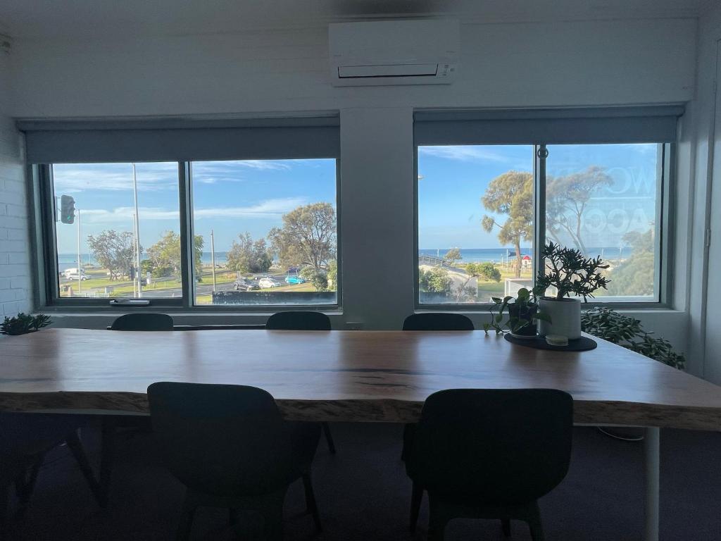 a large wooden table with chairs in a room with windows at Rye Pier Apartment in Rye