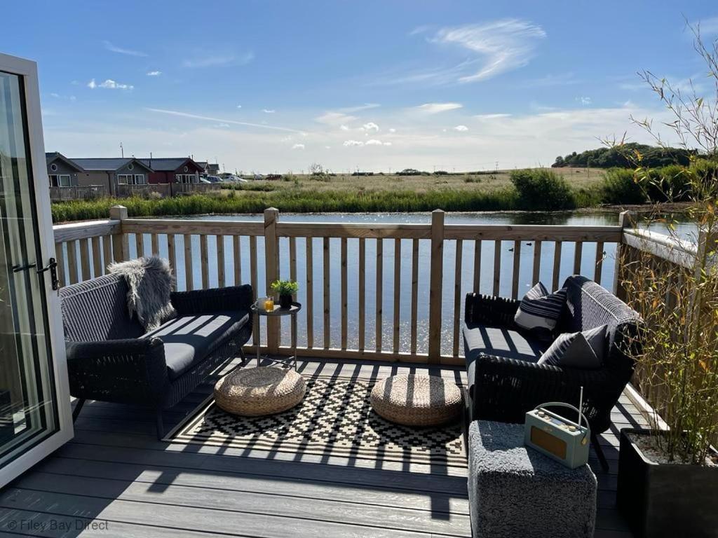 a deck with two chairs and a couch on it at Lakeside Retreat, The Bay Filey, 2 bedrooms with ensuites, parking with EV charger in Filey