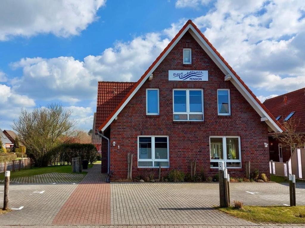 a red brick building with a sign on it at Pension Blaue Nordseewelle in Neuharlingersiel