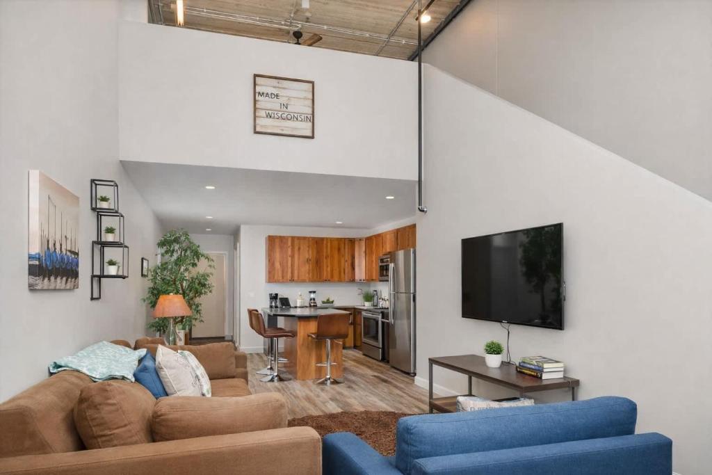 a living room with a couch and a tv and a kitchen at Downtown Appleton Condo 2 Bedroom Loft Sleeps 6 in Appleton