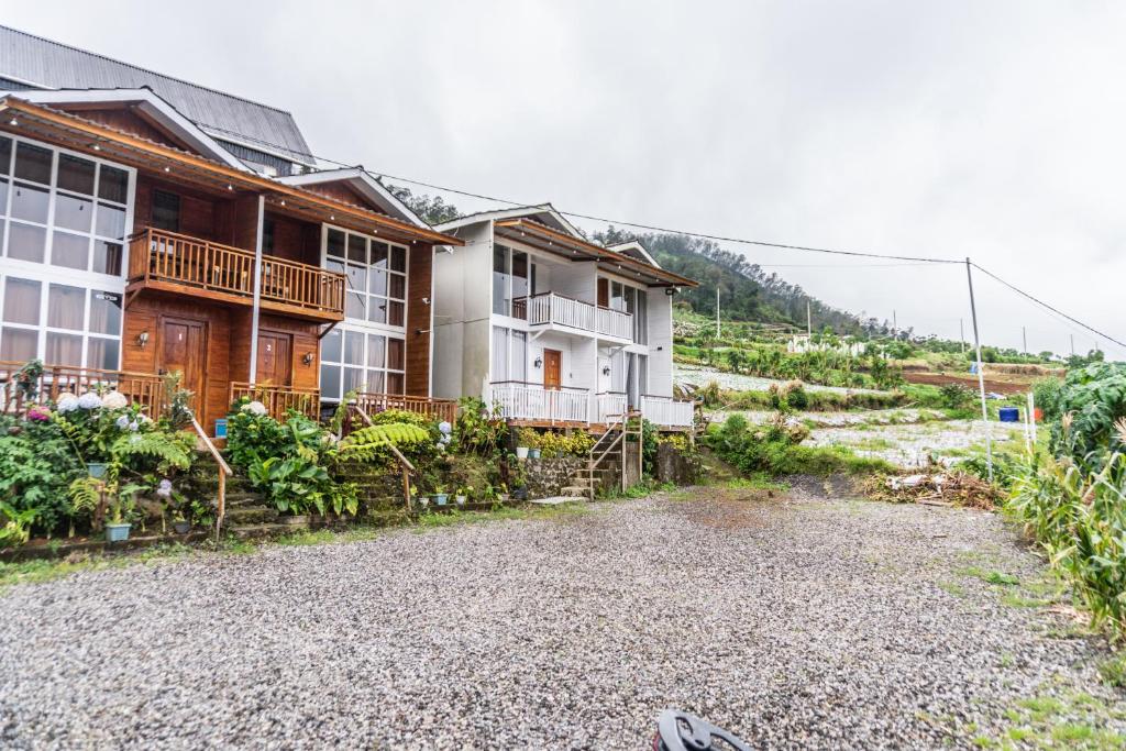 a house on a gravel road next to a mountain at Altura Cabin Dieng in Diyeng