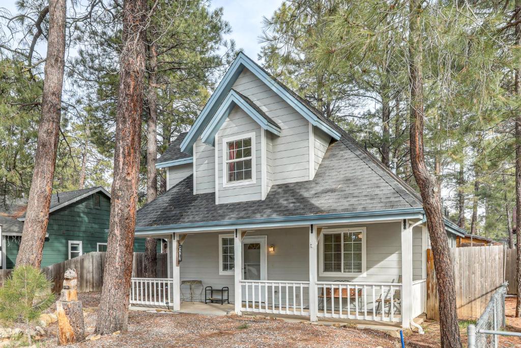 a house with a porch in the woods at Explore the Coconino Forest! Flagstaff Cottage in Flagstaff