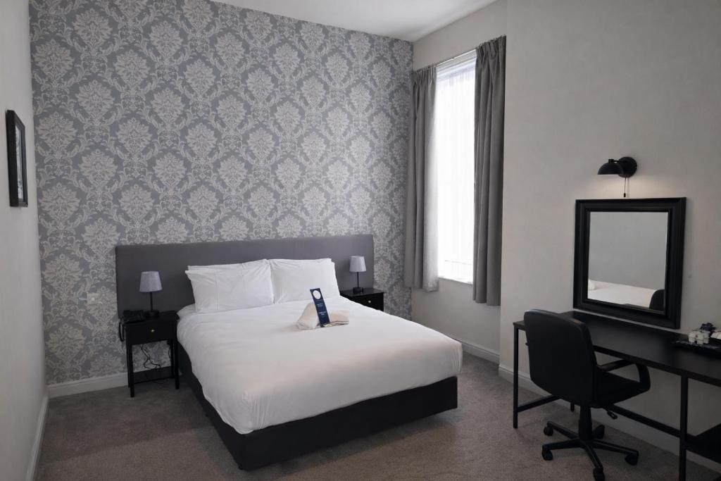 a bedroom with a bed and a desk and a mirror at The County Hotel in Carlisle
