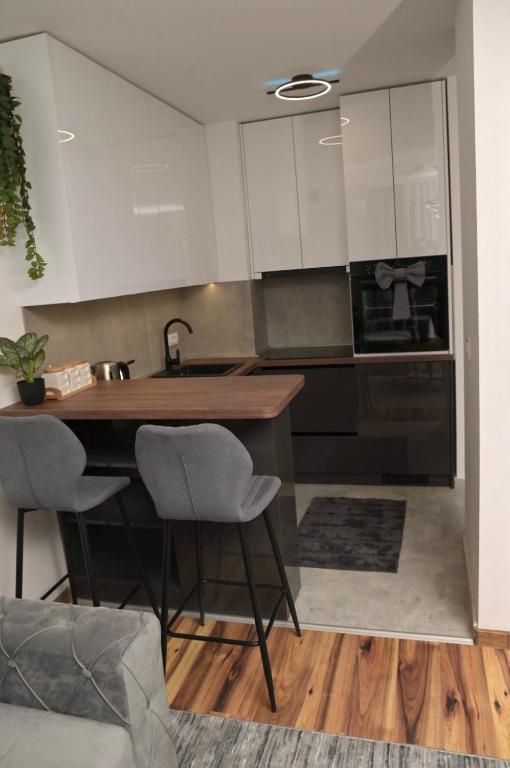 a kitchen with white cabinets and a table and chairs at Stan na dan Pancevo 3 in Pančevo