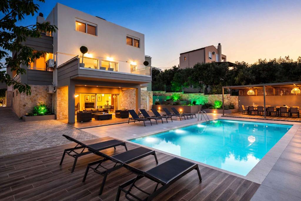 a villa with a swimming pool in front of a house at Villa Aelia - Modern & Ideal for large groups in Galatás