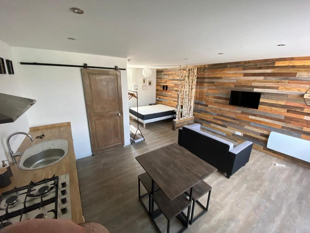 a kitchen and living room with a wooden wall at Le nid de la Brenne in Luant
