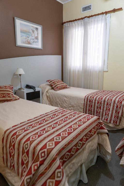 a hotel room with two beds and a window at Hotel Miami in Mar del Plata