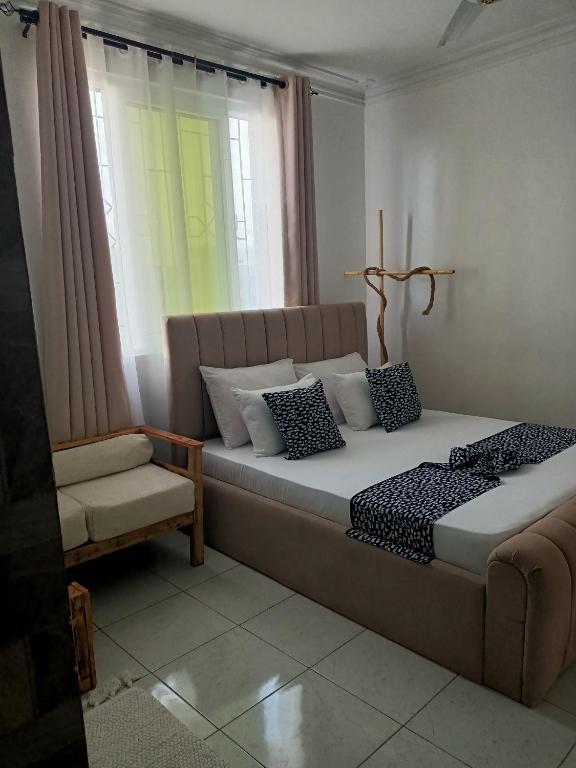 a bedroom with a bed and a chair and a window at Ardina Studio in Mtwapa
