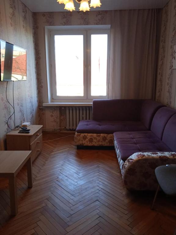 a living room with a purple couch and a window at Gościnne Gniazdo in Będzin