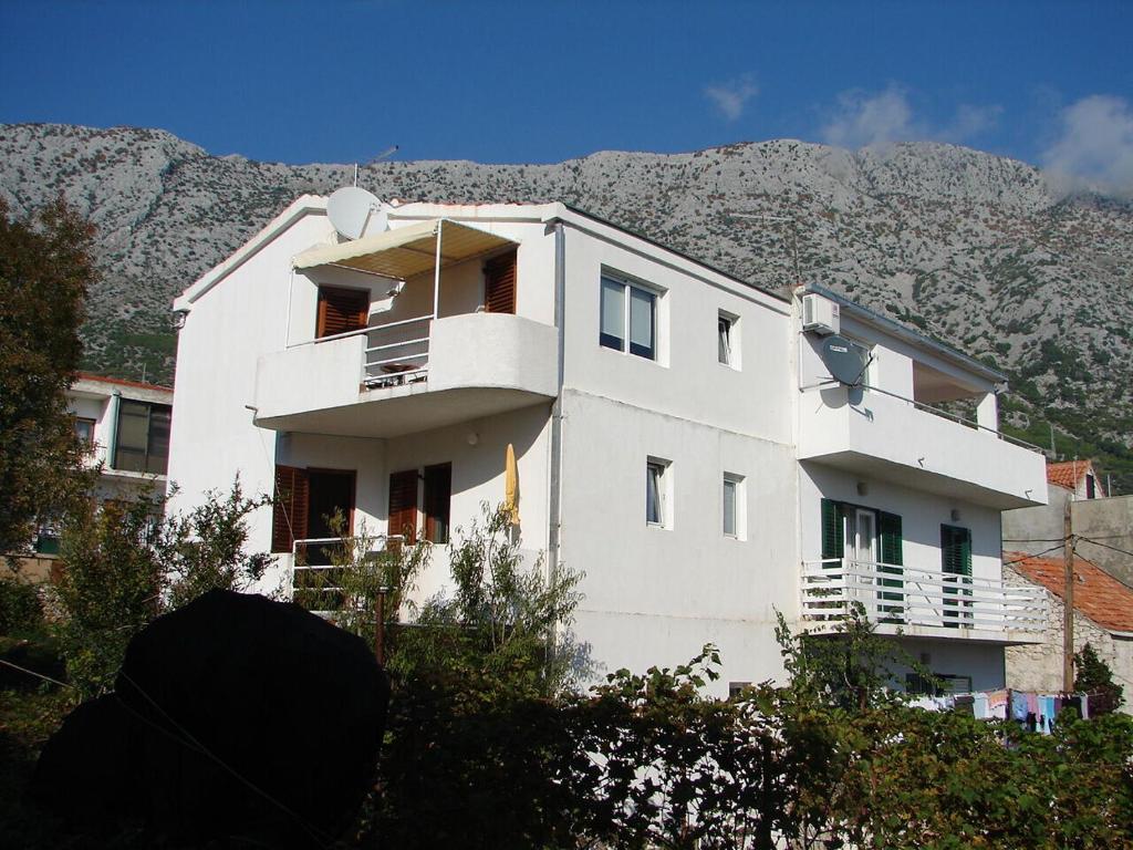 a white house with a mountain in the background at Apartments Vrtina in Igrane