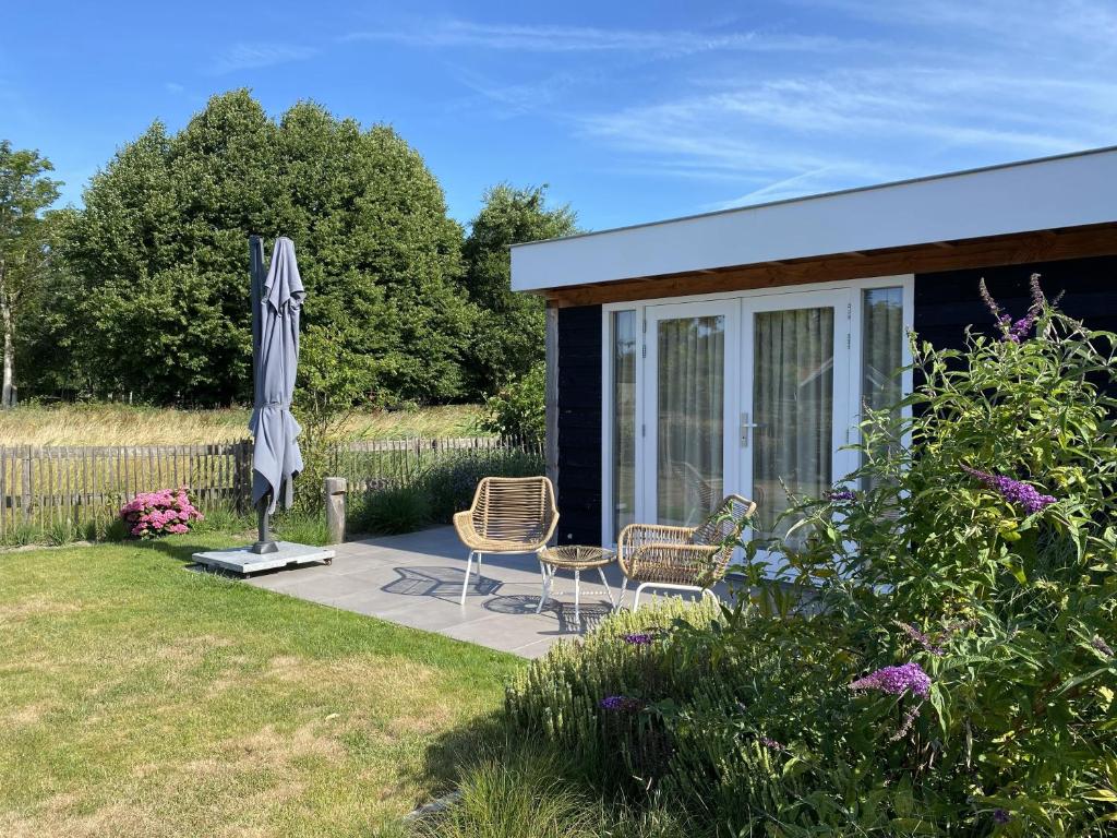 a patio with two chairs and an umbrella and a house at B&B Bed in Burgh in Burgh Haamstede