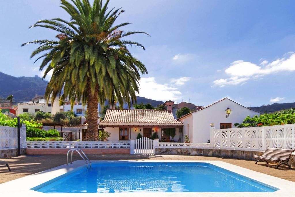 a swimming pool with a palm tree and a house at Casa Rural Milagrosa in Valsequillo