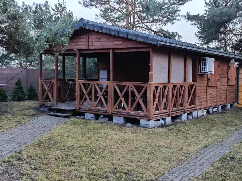 a small wooden cabin with a porch in the grass at Domek letniskowy in Wójcin