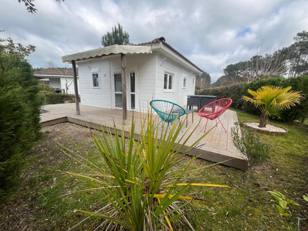 two chairs sitting on a deck in front of a house at Chalet en Parc résidentiel pour 4 personnes à proximité de la plage in Lit-et-Mixe