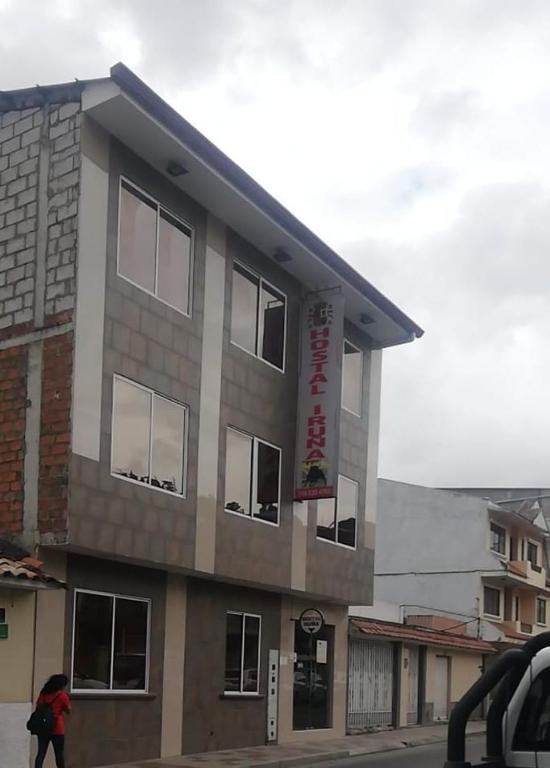 a woman walking in front of a building at Hostal Iruña in Loja