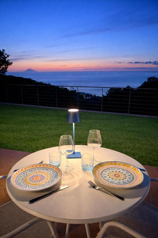 a white table with two plates and wine glasses at BLUE APARTMENT in VILLA ANGISI in Drapia