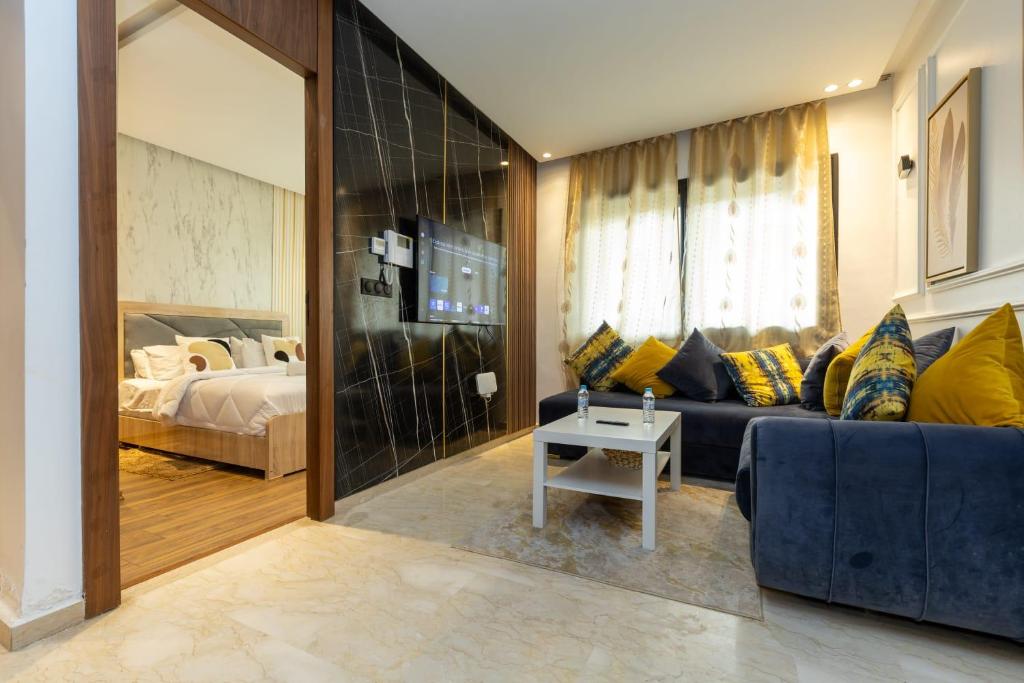 a living room with a blue couch and a bed at Le Nid Doré in Maarif
