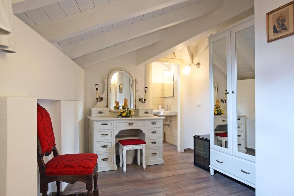 a bathroom with a white vanity and a red chair at Villa Giuliana - Attic apartment in Menaggio