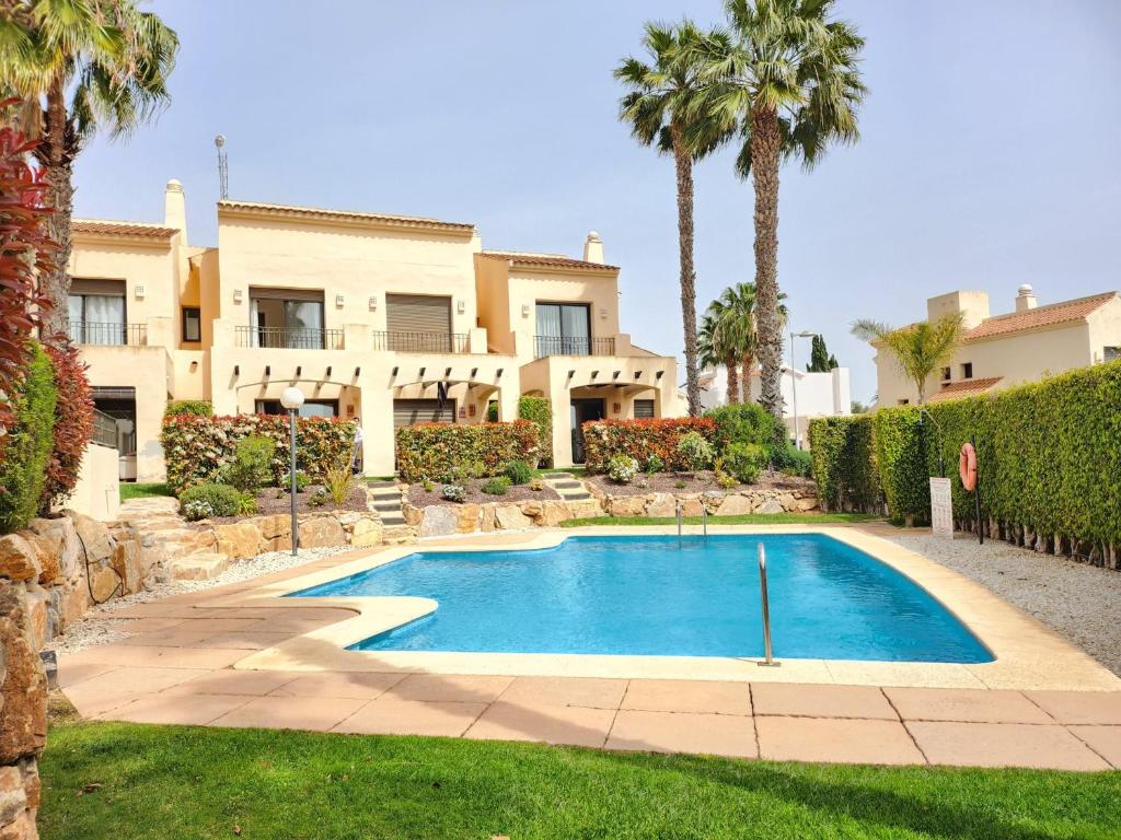 a swimming pool in front of a house with palm trees at RodaGolf Resort Nice Views in San Javier