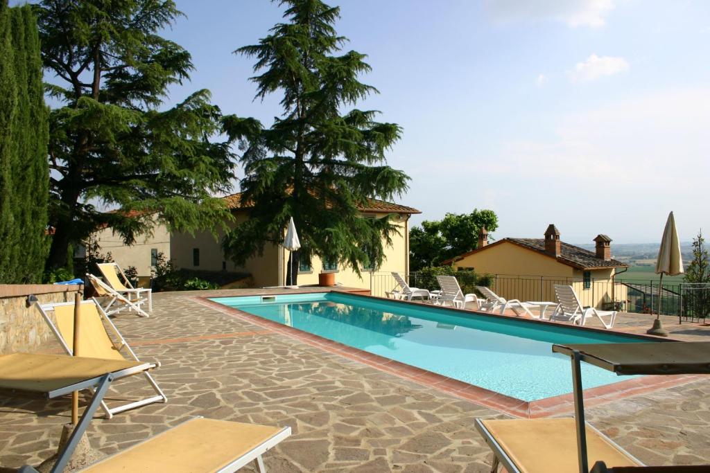 a swimming pool with lounge chairs next to a house at La Maestà Tuscan Sun in Cortona