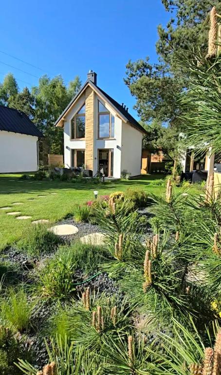 a house with a bunch of plants in front of it at Sjesta al mare, domki z sauną i balią z jacuzzi in Lubiatowo