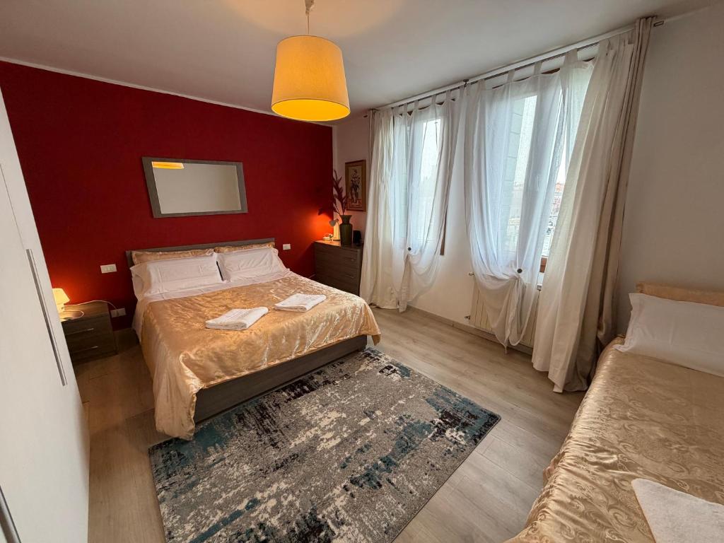 a bedroom with two beds and a red wall at Calle Boldu Venice in Venice