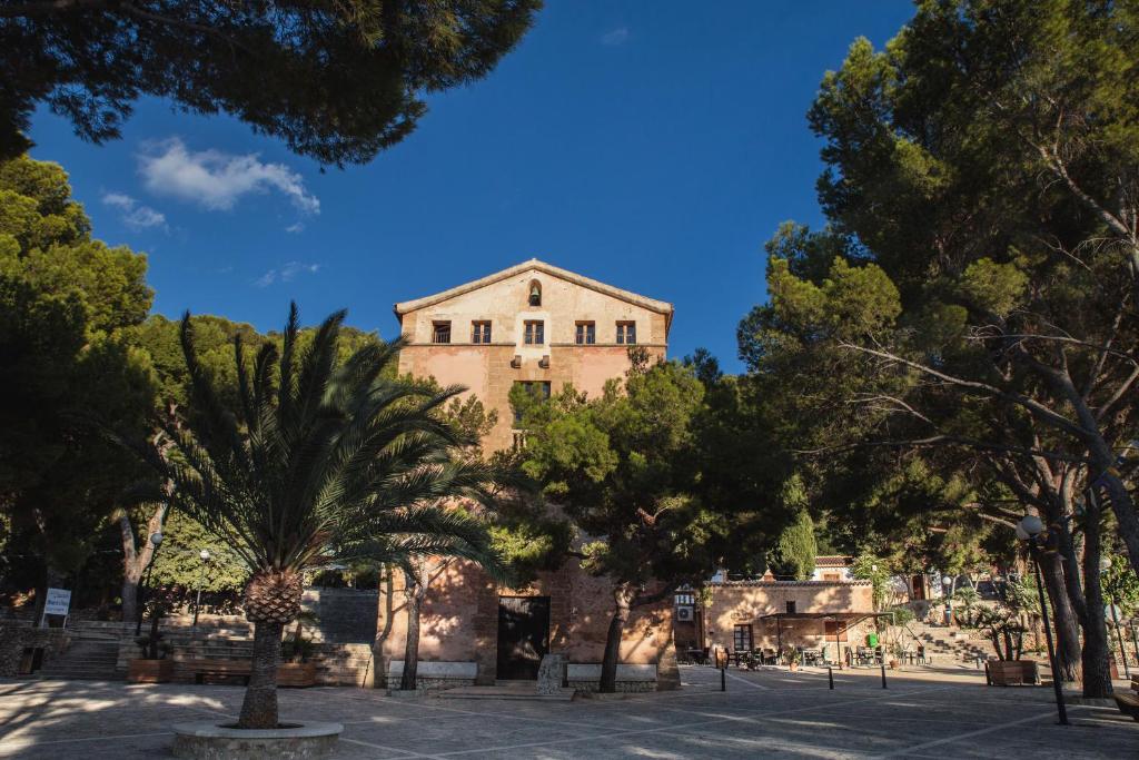 an old building in the middle of trees at Petit Hotel Hostatgeria La Victoria in Alcudia