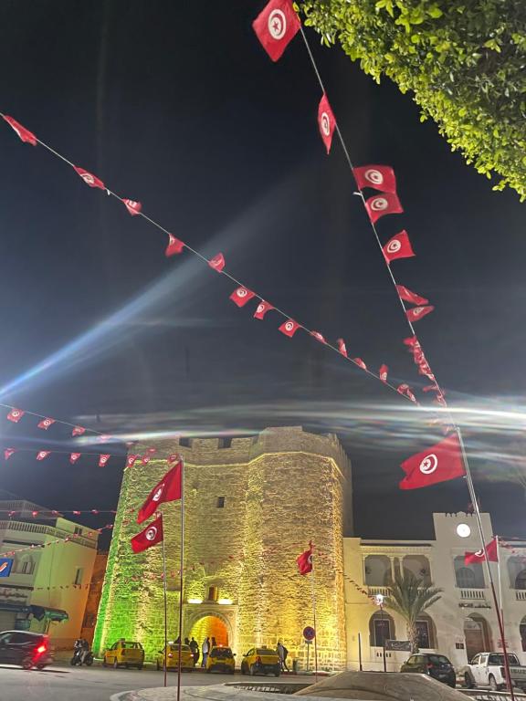 a building with flags in front of it at night at Maison Fatima in Mahdia