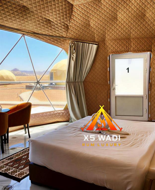a bed in a room with a view of a desert at X5 wadi Rum Luxury in Wadi Rum