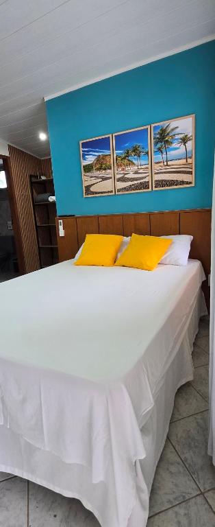 a large white bed with yellow pillows in a room at Flats KENAI in Abraão