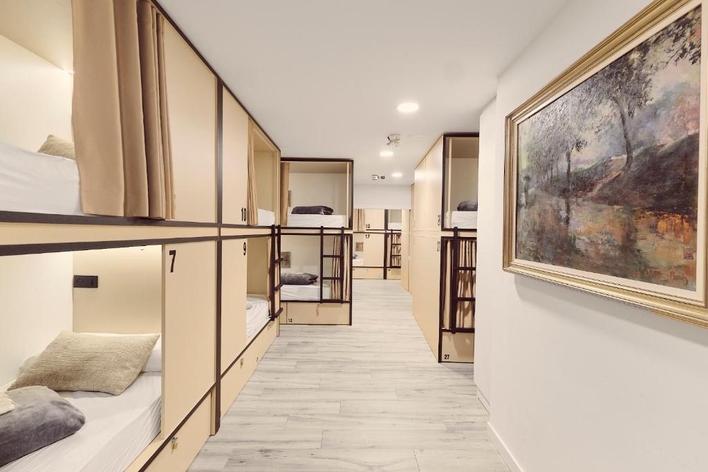 a hallway with beds and paintings on the walls at Albergue San Nicolás in Logroño