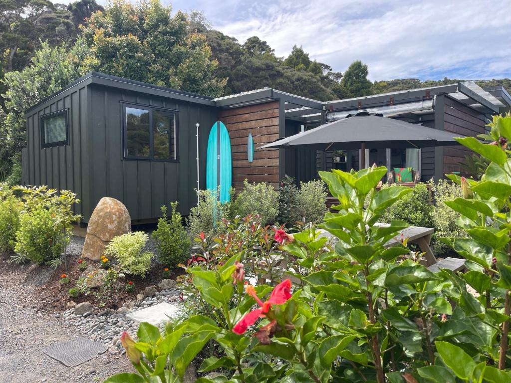 a black tiny house with a blue surfboard on it at Beach Bach Whangaumu Bay Tutukaka in Tutukaka