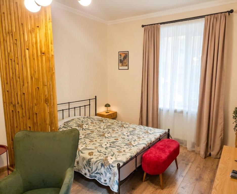 a bedroom with a bed and a chair and a window at The Velvet Stay in Tbilisi City