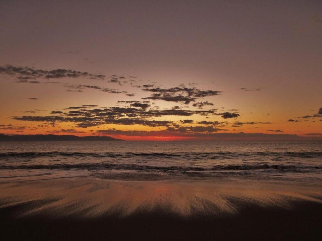 a sunset on a beach with the ocean at Beachfront view Condo beside la Isla Mall in Puerto Vallarta