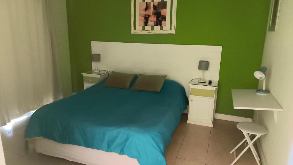 a green bedroom with a bed and two night stands at La Posada del Camino in Dina Huapi
