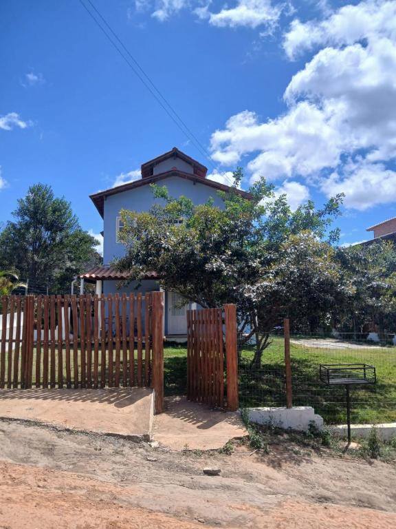 a house behind a wooden fence with a bench at Casa Azul Marichi Hospedagem in Vale do Capao