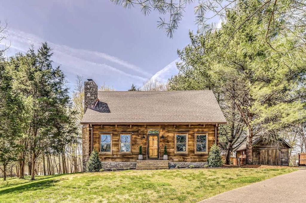 a log cabin house with a porch and trees at Luxury Lakefront Cabin in Castalian Springs