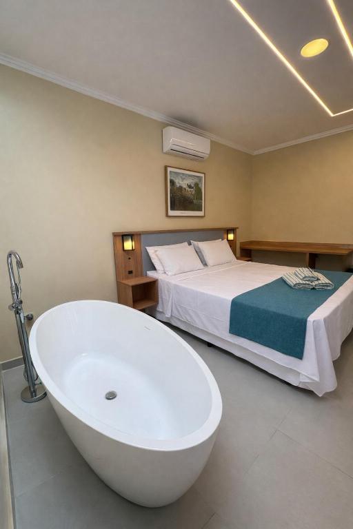 a bathroom with a bath tub next to a bed at Pousada Estalagem do Porto in Arraial do Cabo